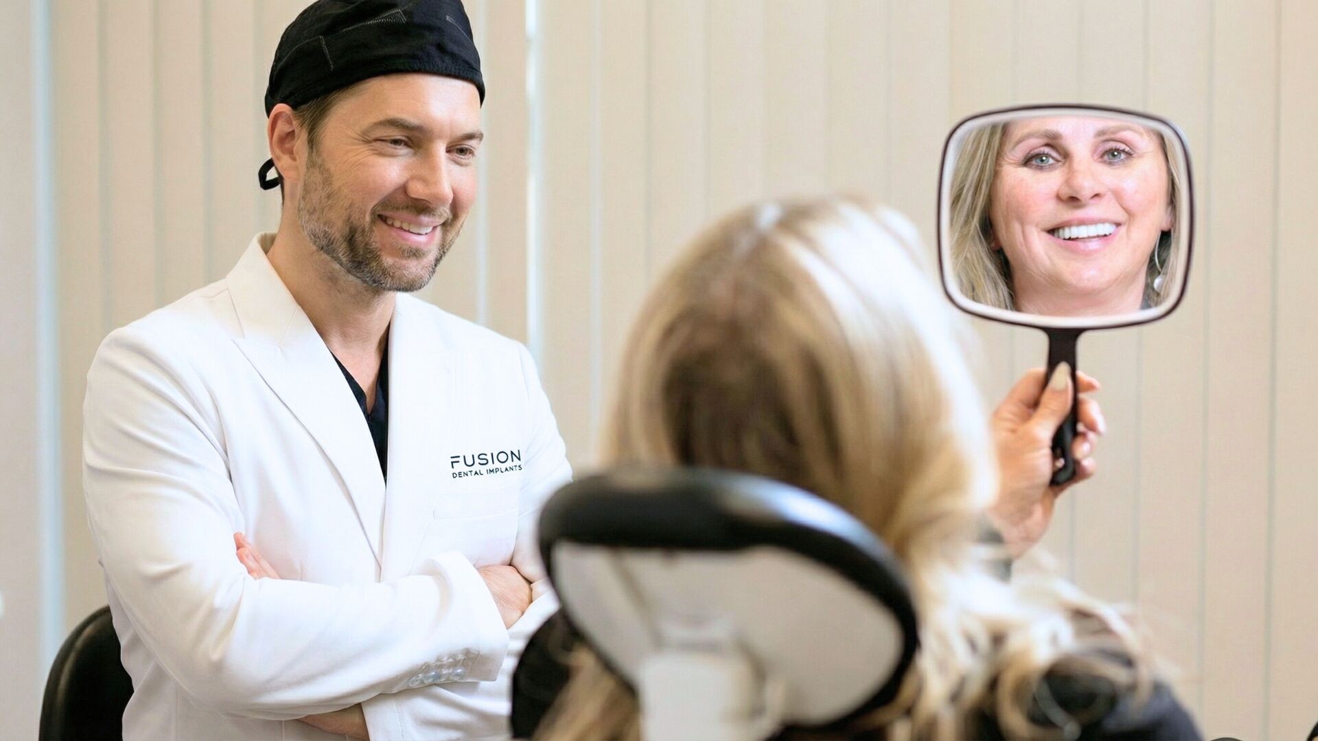 Dr. Antipov with patient admiring her new smile in mirror at Fusion Dental Implants