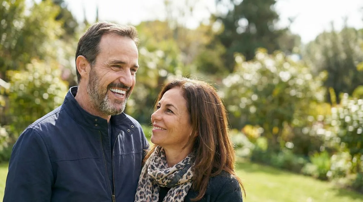 Happy man smiling confidently at a restaurant after full-arch dental implant restoration at Fusion Dental Implants